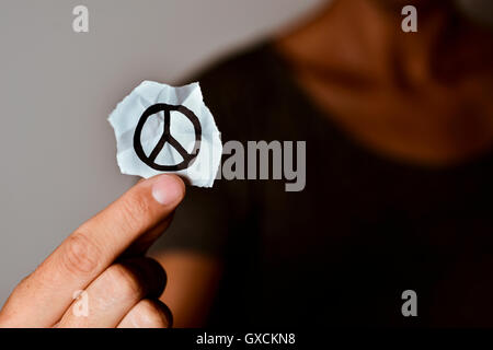 Nahaufnahme eines jungen Mannes zeigt ein Stück Papier mit ein Friedenssymbol es angesaugt Stockfoto