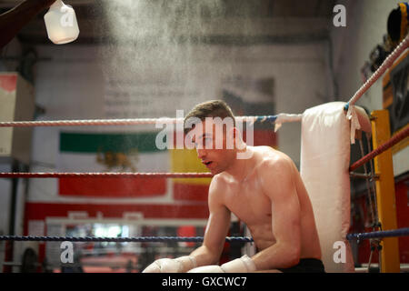 Boxer sitzt in der Ecke des Boxring, erschöpft Stockfoto