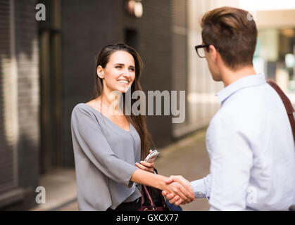 Junge Unternehmer und Unternehmerin schütteln Hände außerhalb Büro, London, UK Stockfoto
