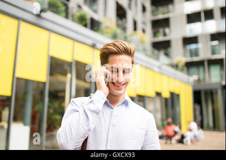 Junge Unternehmer sprechen auf Smartphone außerhalb Büro, London, UK Stockfoto