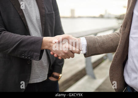 Mitte Schnittansicht von zwei Geschäftsleute Händeschütteln auf Wasser, London, UK Stockfoto