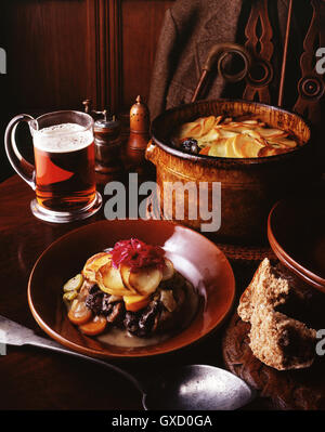 Wildbret-Eintopf, mit Rotkohl, in Scheiben geschnittenen Kartoffeln, Karotten, Zwiebeln und Lauch mit einem Glas Bier und Vollkornbrot Stockfoto