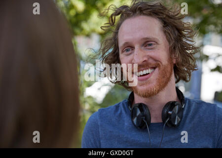 Junges Paar im Freien, von Angesicht zu Angesicht, junger Mann lächelnd Stockfoto