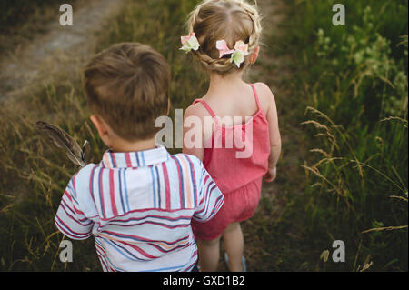 Rückansicht des jungen Mädchens und Zwillingsbruder Hand in Hand in Wiese Stockfoto