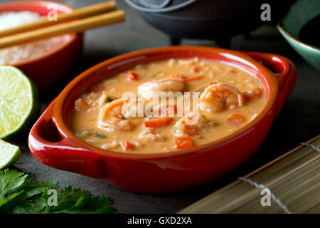 Eine Schüssel mit leckeren Thai Red curry-Kokos-Garnelen-Suppe mit Reis. Stockfoto