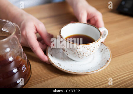 Weiße Tasse Kaffee in der Hand. Barista halten Kaffee Stockfoto