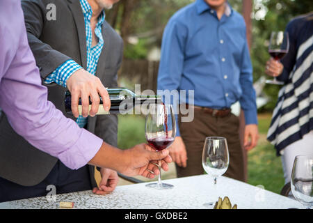 Männliche Hände Gießen Rotwein an Gartenparty Tisch Stockfoto