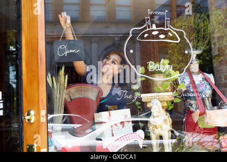Arbeitnehmerin in Bäckerei, drehen Zeichen öffnen Stockfoto