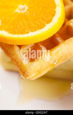 Belgische Waffeln, Honig und Orange auf einem Teller isoliert auf weiss Stockfoto