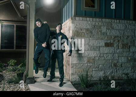 Kaukasische Polizei heben Einbrecher in Handschellen Stockfoto