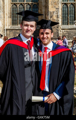 Zwei Hochschulabsolventen posieren für ein Foto vor Canterbury Kathedrale vor ihrer Graduierung Zeremonie, Canterbury, Kent, UK Stockfoto