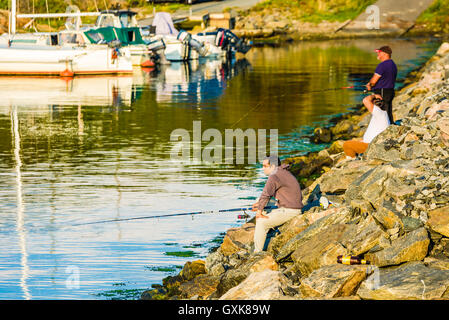 Marstrand, Schweden - 8. September 2016: Dokumentation über drei Männer Angeln am Straßenrand am Abend mit Marina im Hintergrund. Stockfoto