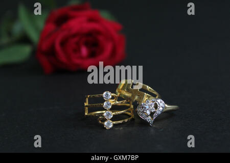 Rote rose mit Trauringe auf schwarzem Hintergrund isoliert. Braut und Bräutigam Ringe. Stockfoto