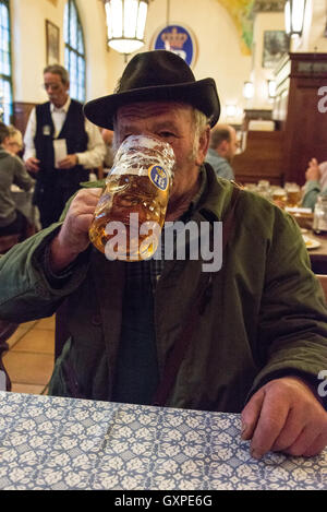 Einheimischen kann gesehen gekleidet in traditioneller Tracht, Münchner Bier aus der berühmten Masse, eine 1-Liter-Krug, trinken und genießen Stockfoto