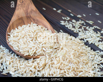 Brauner Reis in den Holzlöffel auf dunklem Holz strukturiert Planken Stockfoto