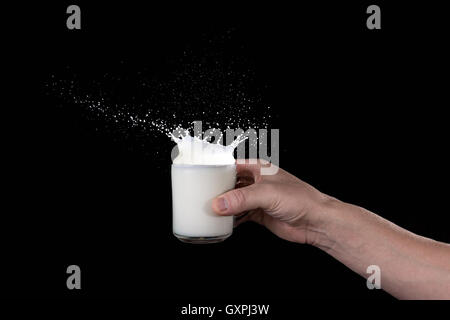 Mannes Hand hält eine Tasse Milch mit einem Schuss auf einem dunklen Hintergrund Stockfoto