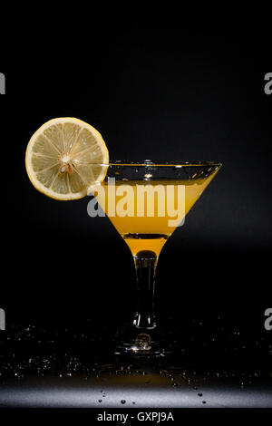 Ein Glas Saft steht auf einem schwarzen Tisch unter der Wassertropfen Stockfoto