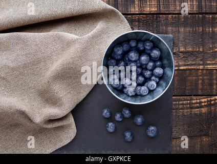 Heidelbeeren in kleinen Stahl-Eimer auf Grunge Holzbrett. Natürliche gesunde Ernährung Stockfoto