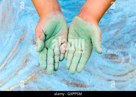 Kleinkind zeigt grüne Hände mit Kreide auf blauem Hintergrund Stockfoto