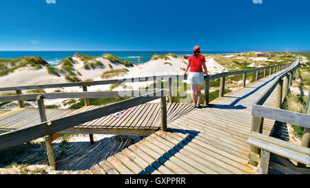 Portugal: Frau genießen Sie Strand und Meer Blick auf einem hölzernen Wanderweg in Praia de Comporta Stockfoto