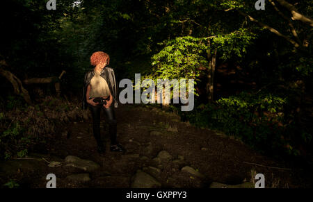 Ein schöner schwarzer Jugendlicher, gefangen im Sonnenlicht, während sie in den Wald geht, Stockfoto