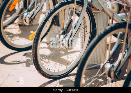 Reihe von geparkten Fahrräder Fahrräder zu vermieten auf Bürgersteig. Nahaufnahme des Rades Stockfoto