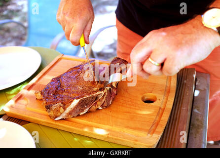 Küchenchef, schneiden Cote de Boeuf Steak auf Schneidbrett aus Holz Stockfoto