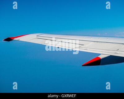 Blick durchs Flugzeugfenster mit Flügel und klarer blauen Himmel Stockfoto