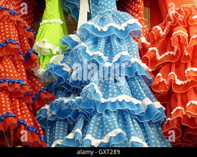 Nahaufnahme eines traditionellen blau, rot, grün und orange Rüschen Flamenco-Kleider mit weißen Flecken und Spitzenbesatz hintereinander hängen Stockfoto