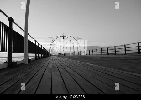 Eindringliches Bild des verlassenen Pier in Southport in schwarz und weiß mit Holzterrassen Stockfoto