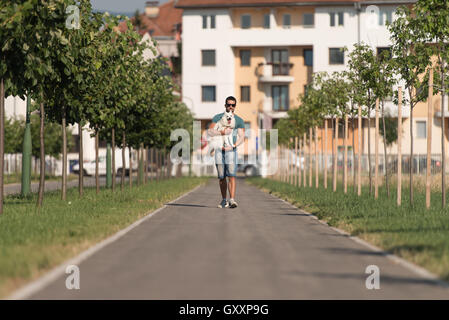 Junger Mann und deutscher Spitz Walk In The Park - er hält den Hund an der Leine Stockfoto