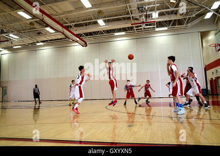 Defensive Teen Basketball-Spieler springt in die Luft in einem erfolglosen Versuch Block Ball. White Bear Lake, Minnesota MN USA Stockfoto