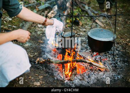 Nahrung wird über einem Feuer In einem alten marschierenden Topf gekocht. Stockfoto