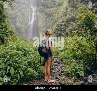 Schöne Frau Wanderer stehend auf Waldweg und wegsehen. Frau mit Rucksack auf Wanderung in der Natur. Stockfoto