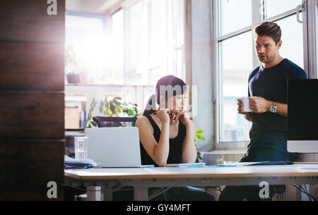Zwei junge executive diskutieren neue Geschäftsideen im Amt. Kolleginnen und Kollegen gemeinsam an Papierkram. Frau sitzt an ihrem Schreibtisch Stockfoto