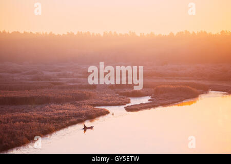 Ruhigem See, Fluss und Rudern Angelboot/Fischerboot am wunderschönen Sonnenaufgang In Herbstmorgen. Fischer ist im Boot Stockfoto