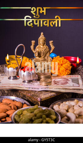 Happy Diwali Gruß Karte zeigt Öllampe oder Diya mit Crackern, süß oder Kozhikode, trockene Früchte, indische Banknoten, Blumen Stockfoto