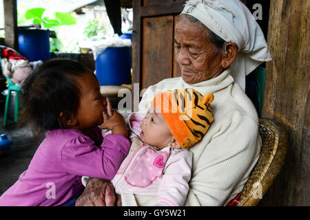 Philippinen, Cordillera Highlands, Bontoc, Samoki Dorf, Igorot Menschen, Samoki Stamm, alte Frau nehmen sorgen ihrer Enkel als die Eltern im Ausland arbeiten / PHILIPPINEN, Kordilleren, Bontoc, Samuki Dorf, Igorot Volksgruppe, Samoki Clan, Alte Frau Pingao Chinalpan, Geb. 1936, Kuemmert Sich um Ihre hat, sterben Eltern Arbeiten Im Ausland Stockfoto