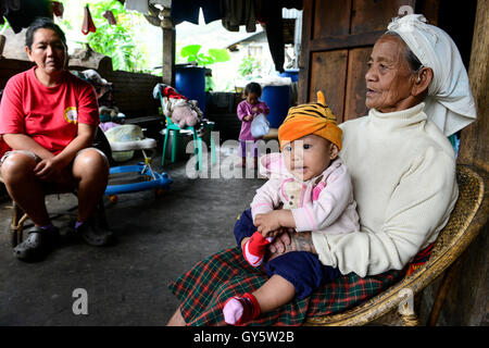 Philippinen, Cordillera Highlands, Bontoc, Samoki Dorf, Igorot Menschen, Samoki Stamm, alte Frau nehmen sorgen ihrer Enkel als die Eltern im Ausland arbeiten / PHILIPPINEN, Kordilleren, Bontoc, Samuki Dorf, Igorot Volksgruppe, Samoki Clan, Alte Frau Pingao Chinalpan, Geb. 1936, Kuemmert Sich um Ihre hat, sterben Eltern Arbeiten Im Ausland Stockfoto