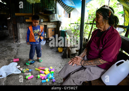 Philippinen, Cordillera Hochland, Bontoc, Samoki Dorf, Igorot Menschen, Samoki Stamm, alte Frau mit Tattoo und Schlange Skelett im Haar stört ihrer Enkel der Eltern im Ausland arbeiten, Senioren sorgen für Kinder Stockfoto