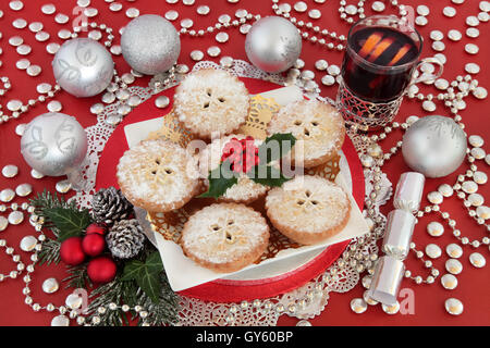 Hackfleisch Torte Weihnachten Kuchen, Glühwein, Wein trinken, Holly, Winter grün und Silber Cracker und Kugeln auf rotem Grund. Stockfoto