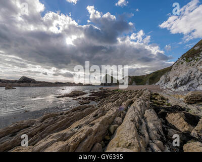 Landschaft, die felsige Küste der Mann O'War Strand an einem feinen Sommertag mit Durdle Door Landzunge im Hintergrund darstellen. Stockfoto