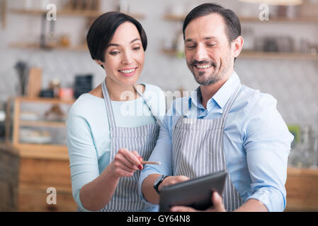 Zwei Unternehmer mit Schürzen stehen im café Stockfoto