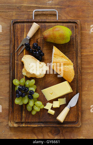 Käse vom Brett mit Trauben, Birnen und baguette Stockfoto