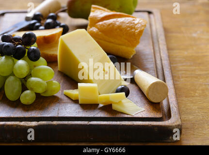 Käse vom Brett mit Trauben, Birnen und baguette Stockfoto