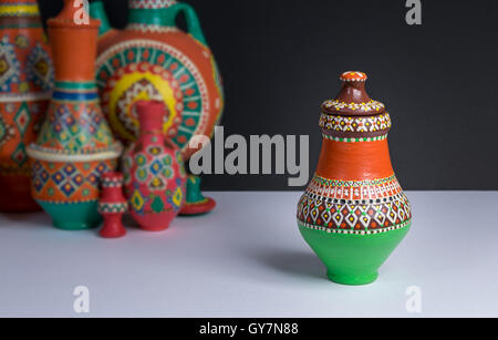 Stillleben mit einer kunstvollen bunten Keramik-Vase auf Hintergrund unscharf Gruppe von bunte Vasen, weißen Tisch und schwarze Wand Stockfoto