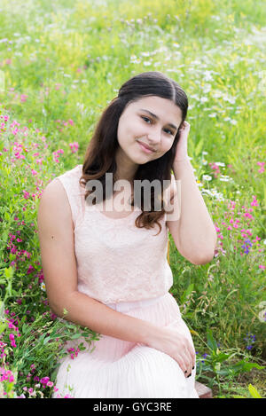 Hübsches Mädchen sitzt auf reich Wiese Stockfoto