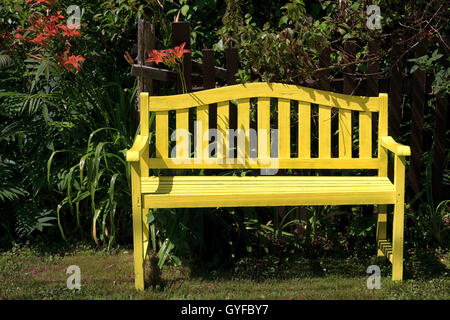 Gelbe Holzbank in einem Garten oder Park. Stockfoto