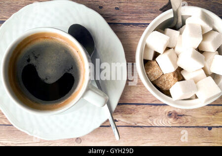 Tasse Kaffee und verschiedene Zucker auf einem Holztisch Stockfoto