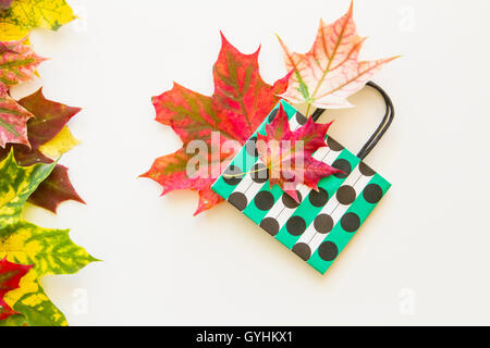 Buntes Herbstlaub und Polka Dot Papiertüte auf weißem Hintergrund. Flach zu legen. Ansicht von oben Stockfoto